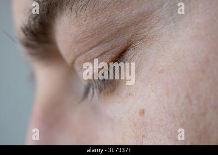 Makro-Nahaufnahme, detaillierte Profilansicht eines männlichen Gesichts mit geschlossenen Augen mit natürlicher Hautstruktur und Wimpern Stockfoto