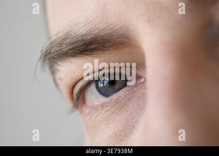 Extreme Nahaufnahme eines nicht erkennbaren Kaukasiers mit blauen Augen, der direkt in die Kamera blickt Stockfoto