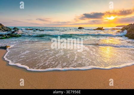 Sandstrand eines schwarzen Meeres bei Sonnenaufgang. bulgarische Szene in der heißen Sommerferienzeit. Wunderschöner Blick auf die Wellen, die den Sand im Morgenlicht waschen. Generi Stockfoto