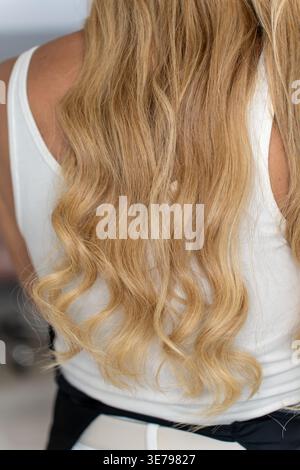 Gesundes langes blondes glänzendes welliges Haar Rückansicht. Blondes Lockiges Haar. Schönheitssalon und Haarpflegekonzept. Stockfoto