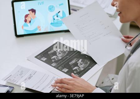 Weibliche Ärztin, die IVF-Dokumente und Ultraschallergebnisse überprüft Stockfoto