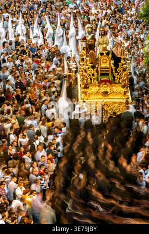 Das Geheimnis der Bruderschaft La Bofetá während der Karwoche in Sevilla, Spanien. Die langsame Belichtung fängt die lebendige Atmosphäre und den Raum der religiösen Prozession ein Stockfoto