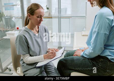 Weibliche Krankenschwester beratende Erwachsene Frau während des Arztbesuchs Stockfoto