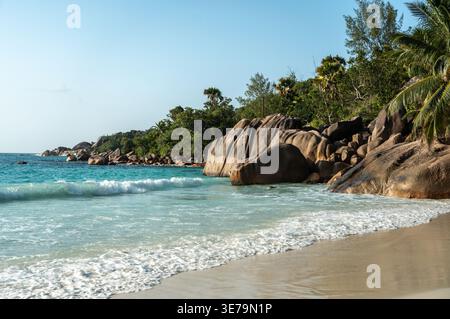 Anse Lazio Strand auf den Seychellen mit türkisfarbenem Meer, Granitfelsen, weißem Sand, üppigen Palmen und Schwimmern, die das tropische Paradies genießen, ideal für Tri Stockfoto
