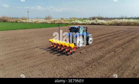 Luftaufnahme eines blauen Traktors mit gelben und orangefarbenen Komponenten auf einem braunen Boden, Sremska Mitrovica, Vojvodina, Serbien. Stockfoto