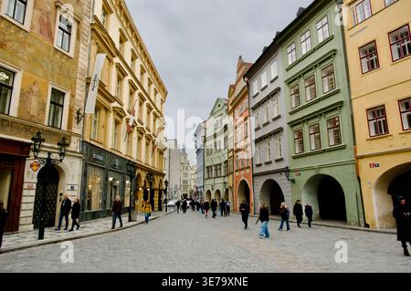 Eine belebte europäische Altstadt mit farbenfrohen historischen Gebäuden und Arkaden, Kopfsteinpflasterpflasterpflaster und lässigen Fußgängern darunter Stockfoto