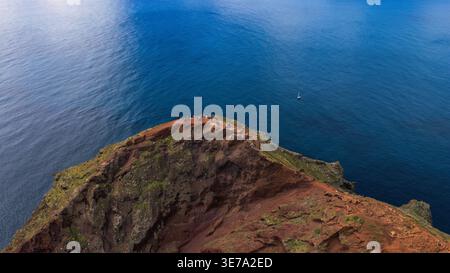 Die Luftaufnahme zeigt Wanderer auf dem rostroten Kamm von Ponta de Sao Lourenco, Madeira, Portugal, Mittagslicht, klarer Himmel, zerklüftete Klippen, karge Vegetation, Stockfoto