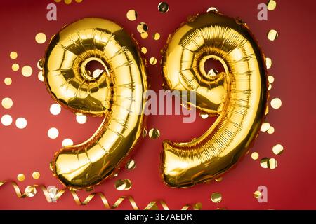 99. Geburtstag. Goldene festliche Ballons Zahl 99-jähriges Jubiläum auf rotem Hintergrund mit Konfetti. Geburtstag oder Hochzeit. Stockfoto