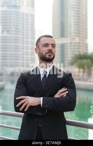Geschäftsmann steht selbstbewusst in der Dubai Marina in den Vereinigten Arabischen Emiraten. Moderne Gebäude spiegeln den Erfolg im Finanzwesen wider. Stockfoto