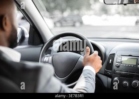 Zugeschnittenes Bild eines schwarzen Geschäftsmannes, der während der Fahrt im Auto sitzt Stockfoto