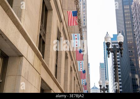 Weite Aufnahme des Stadtzentrums Chicagos, mit der vor den berühmten Wolkenkratzern der Stadt stolzer Flagge von Chicago und den USA flattern Stockfoto