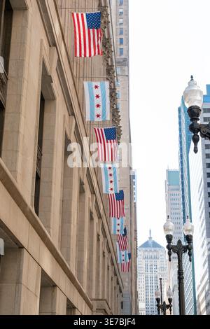 Eine vertikale Aufnahme der Innenstadt von Chicago, mit den Flaggen von Chicago und den Vereinigten Staaten, die stolz vor den berühmten Wolkenkratzern winken Stockfoto