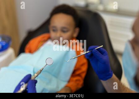 Schwarzer Junge bei Zahnbehandlung mit männlichem Zahnarzt in der Klinik Stockfoto