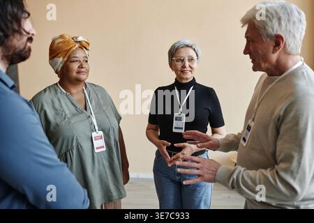 Seitliches Porträt eines Seniorenmannes, der mit einer Gruppe von Menschen in einer Selbsthilfegruppe spricht Stockfoto