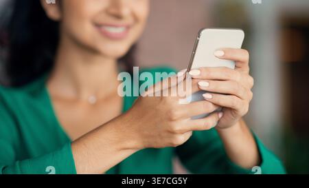Indische Frau, die ihr Smartphone benutzt, sitzt im Café Stockfoto