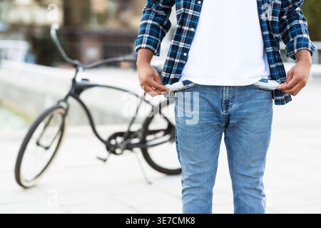 Schwarzer Mann in Jeans mit leeren Taschen, die tagsüber auf der Straße stehen Stockfoto