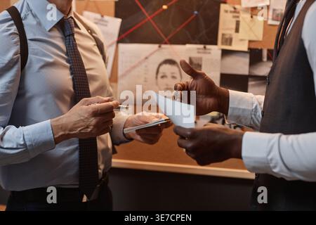 Hände von schwarzen und kaukasischen männlichen Detektiven, die Notizen während des Gesprächs im Amt halten Stockfoto