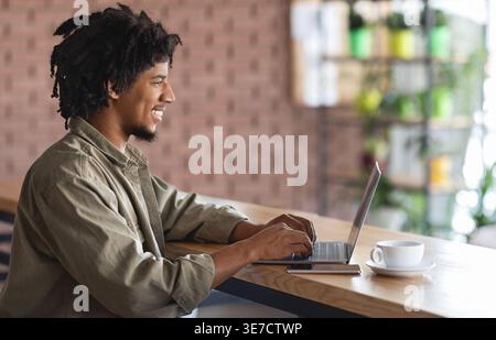 Lächelnder schwarzer Mann mit Afro, der am Tisch im Café sitzt Stockfoto