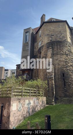 Alter Steinturm mit moderner hölzerner Erweiterung unter klarem Himmel. Stockfoto