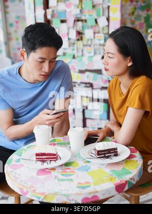 Asiatischer Mann, der mit seinem Mädchen im Café am Tisch sitzt Stockfoto