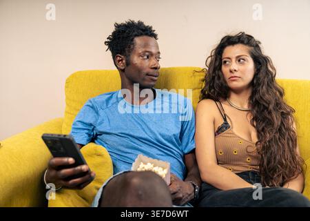 Schwarze männliche und kaukasische weibliche Paare behandeln einander schweigend, nachdem sie zu Hause auf dem Sofa sitzen Stockfoto