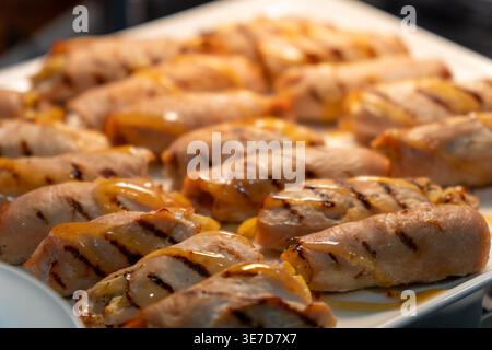 Nahaufnahme köstlicher gegrillter Fleischbrötchen mit einer herzhaften Glasur und sichtbaren Grillspuren, wunderschön präsentiert auf einer weißen Platte für Catering, Buffet, o Stockfoto