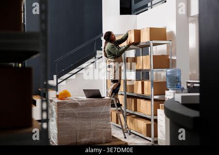 Mitarbeiter des Storehouse nehmen Kartons aus dem Regal und bereiten Kundenbestellungen im Lagerraum vor. Afrikanisch-amerikanischer Lagerleiter, der an den Versanddetails für Pakete im Lager arbeitet Stockfoto