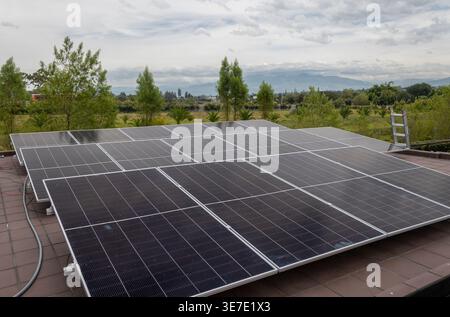 Installation von Sonnenkollektoren auf dem Dach, die sauberen Strom mit natürlicher Landschaft im Hintergrund erzeugen. Nachhaltige Energielösung für den Wohnbereich. Stockfoto