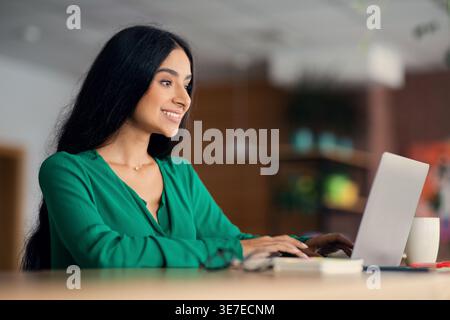 Indische Frau, die im Café am Tisch sitzt Stockfoto