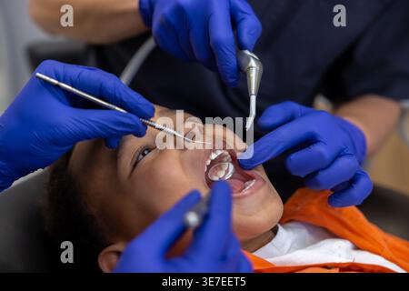 Schwarzer Junge bei Zahnbehandlung mit männlichen Zahnärzten in der Klinik Stockfoto