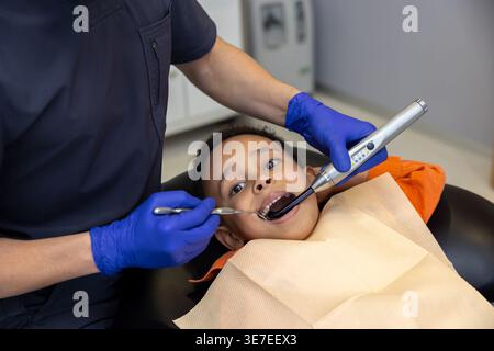 Schwarzer Junge bei Zahnbehandlung mit männlichem Zahnarzt in der Klinik Stockfoto