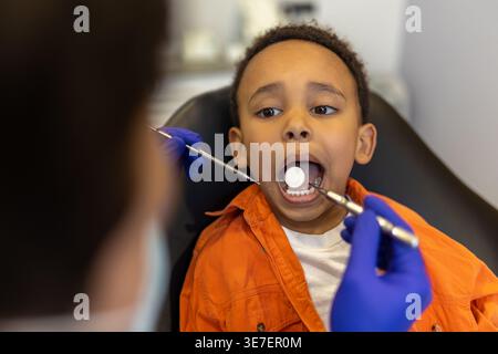 Schwarzer Junge bei Zahnbehandlung mit männlichem Zahnarzt in der Klinik Stockfoto