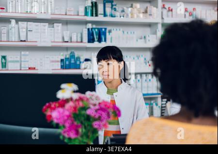 Japanische Apothekenassistentin mit Computer, der an der Theke in der Apotheke steht Stockfoto