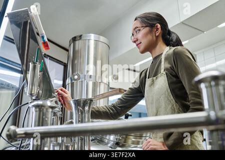 Frau mit Schürze, die in der Fabrik steht Stockfoto