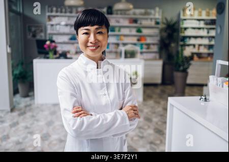 Japanische Apothekerin steht mit gekreuzten Armen in der Apotheke Stockfoto