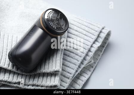 Stoffrasierer und Pullover auf grauem Hintergrund, Nahaufnahme Stockfoto