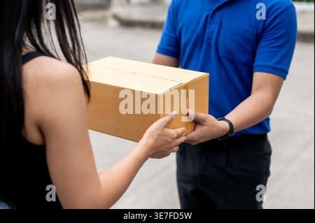Zugeschnittenes Bild einer asiatischen Kundin, die tagsüber vom Liefermann vor ihrem Haus ein Paket erhält Stockfoto