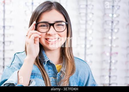 Nicaraguanische Kundin in Jeansjacke mit Brille im optischen Geschäft Stockfoto