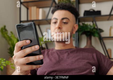 Mann mit gemischter Rasse, der zu Hause auf dem Sofa sitzt Stockfoto