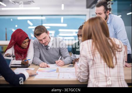 Konzentrierte Gruppe von Geschäftsleuten, die gemeinsam am Tisch sitzen und Geschäftspläne im Büro besprechen Stockfoto
