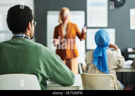 Rückansicht eines gemischten männlichen Schülers, der Diskussionen zuhört, während er im Klassenzimmer am Tisch sitzt Stockfoto