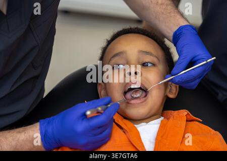 Schwarzer Junge bei Zahnbehandlung mit männlichen Zahnärzten in der Klinik Stockfoto