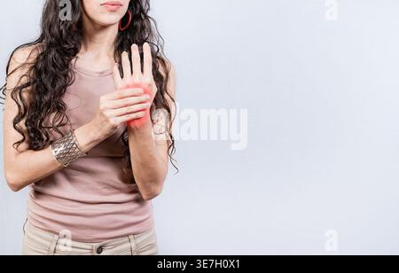 Hispanische Frau mit Handschmerzen, die vor weißem Hintergrund im Studio steht Stockfoto