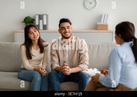 Nahöstliches Paar, das weiblichen Psychologen zuhört, während er in der Klinik auf der Couch sitzt Stockfoto