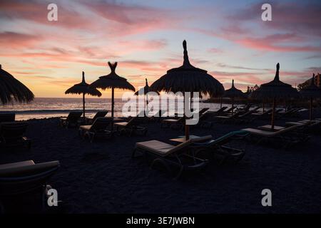 Sunset Beach mit Sonnenliegen und Strohschirmen Stockfoto