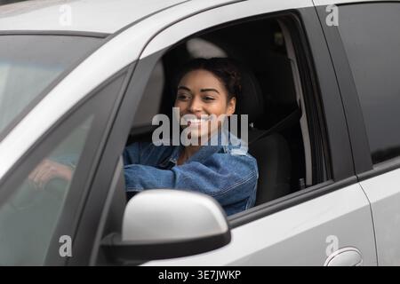 Lächelnde schwarze Fahrerin, die tagsüber Auto fährt Stockfoto