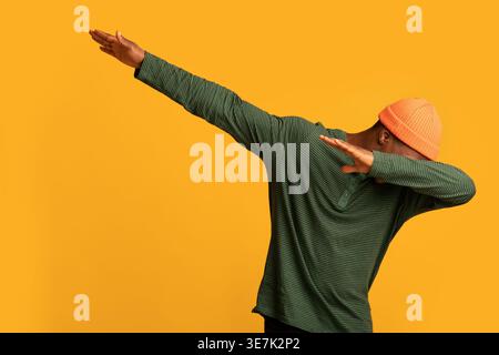 Schwarzer Mann in Beanie, der im Studio vor gelbem Hintergrund steht Stockfoto