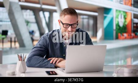 Selbstbewusster Geschäftsmann, Der Online-Seminar Von Laptop In Modern Workspace Führt Stockfoto