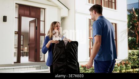 Fröhlicher Lieferer Präsentiert Frisch Gereinigten Mantel Im Professionellen Wäscheservice Stockfoto