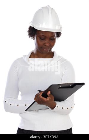 Schwarze Ingenieurin mit Schutzhelm auf dem Klemmbrett, die vor weißem Hintergrund steht Stockfoto